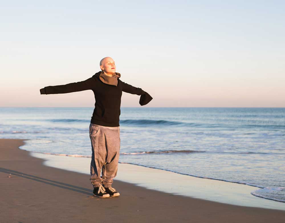 CareAcross-woman-arms-wide-on-the-beach